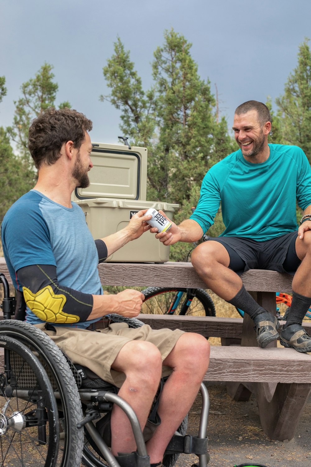 smiling man giving man beer can