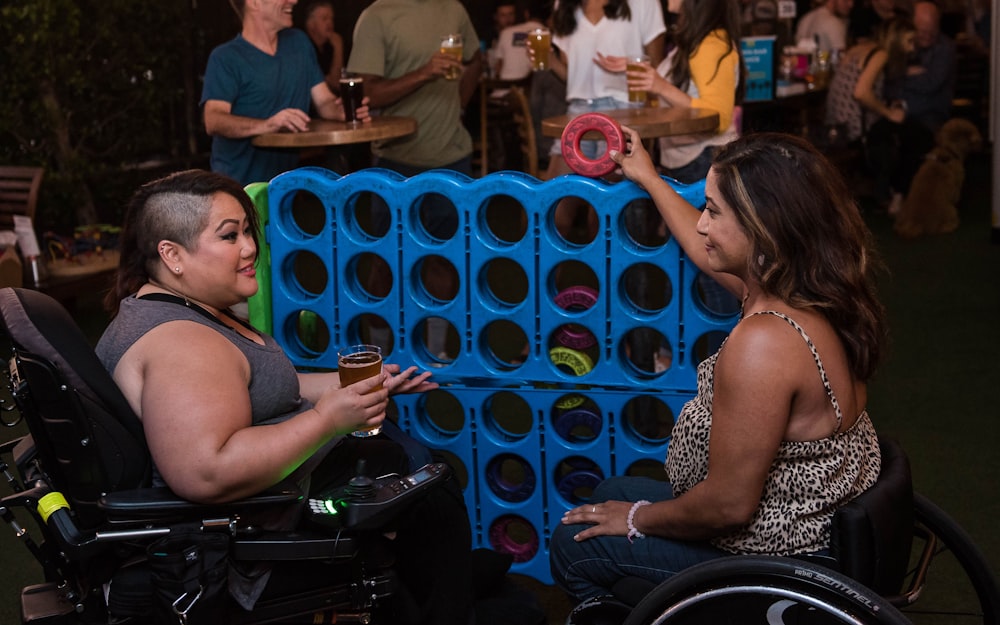 two women sitting on wheelchairs near people