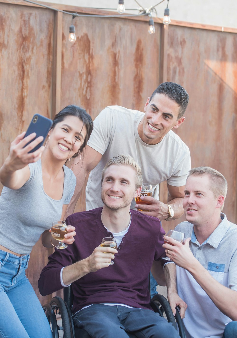 man sitting on wheelchair taking selfie with woman and two men