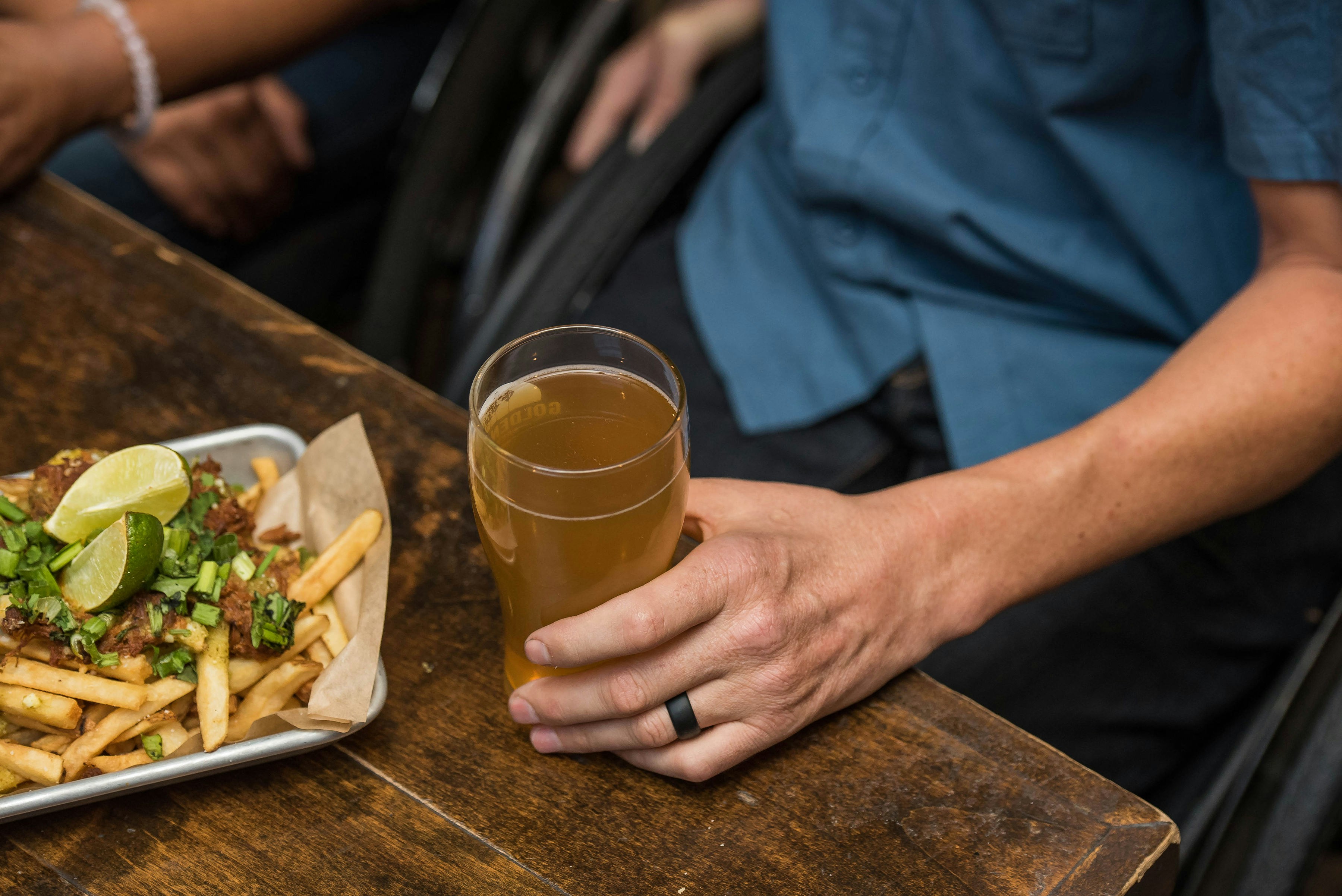 Person with a glass of beer and chips at a table