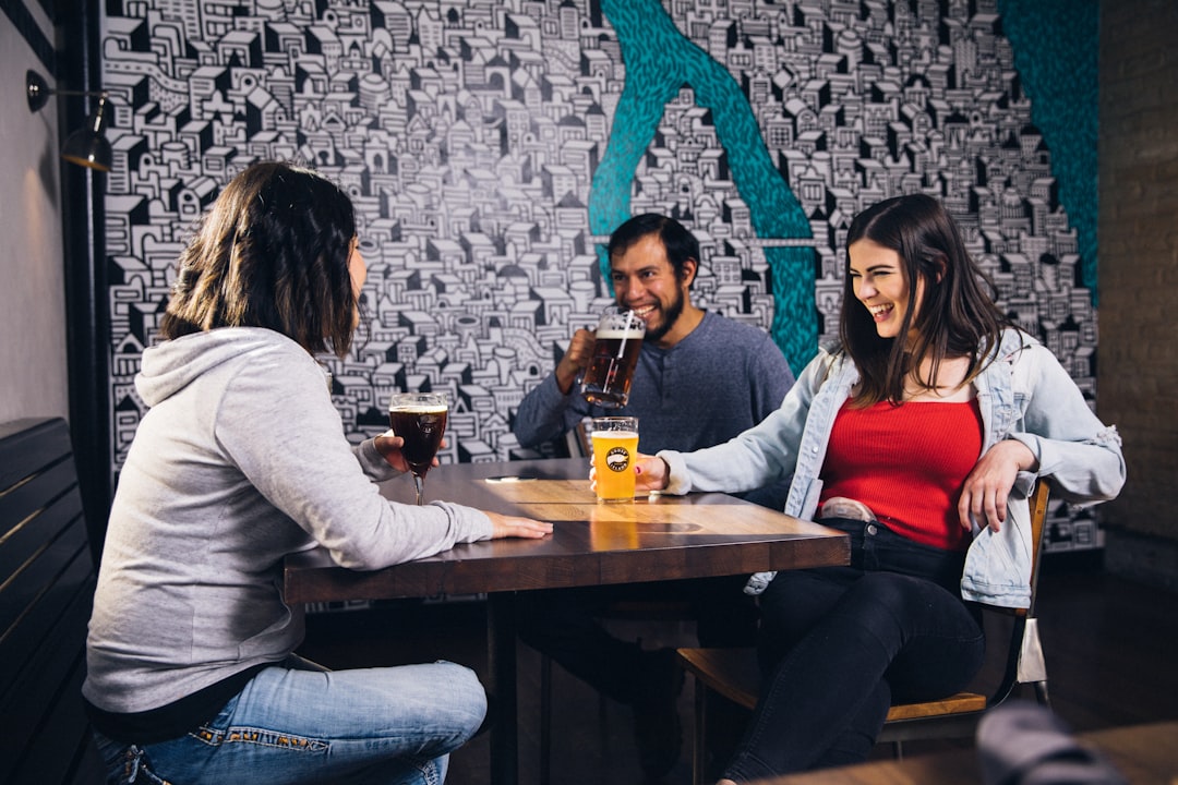 laughing man sitting near two women beside wooden table