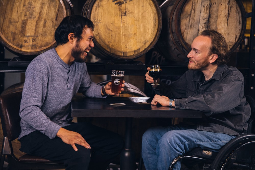 dois homens sentados em uma mesa com taças de vinho