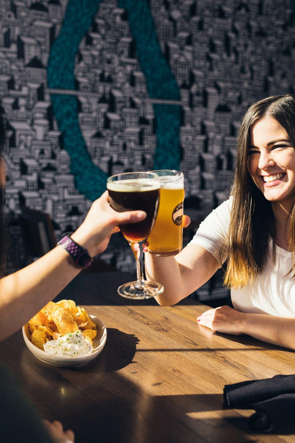 smiling woman sitting on chair while holding beer glass