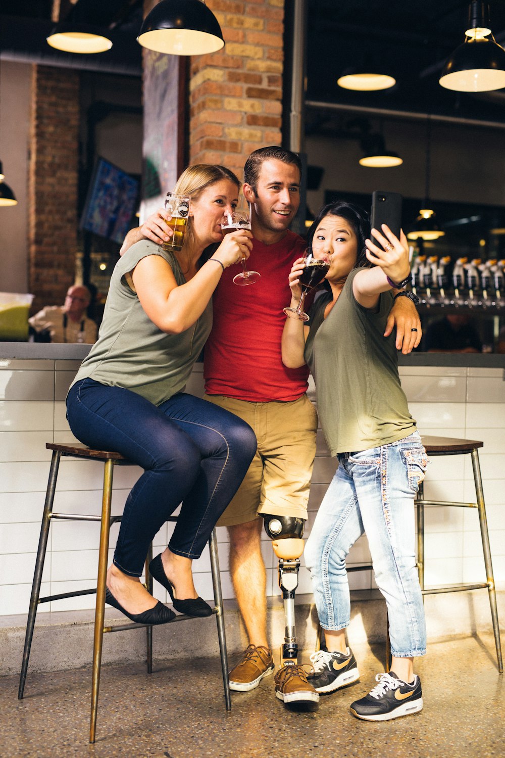 hombre entre dos mujeres tomando selfie