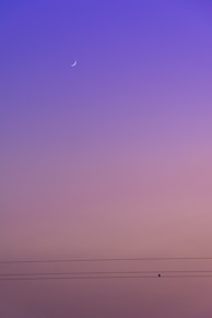 a purple sky with a half moon in the distance