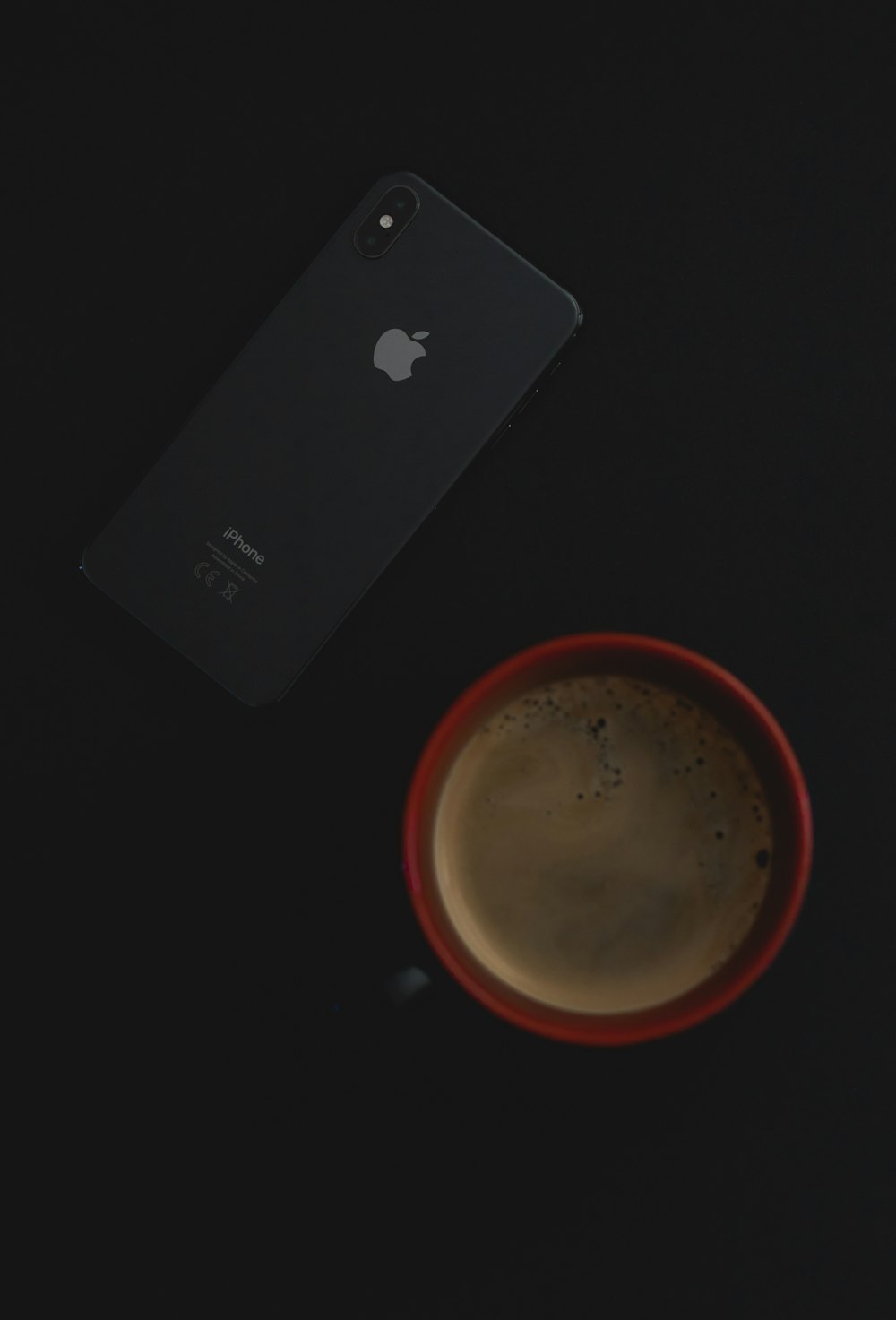 cup of coffee in red cup beside iPhone