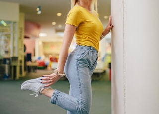 woman smiling and standing on one leg beside pillar