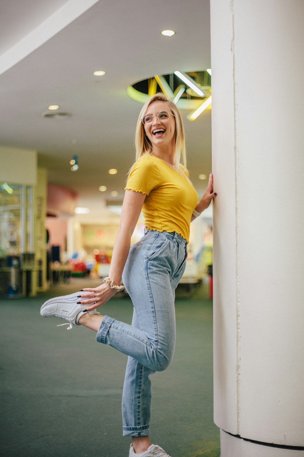 woman smiling and standing on one leg beside pillar