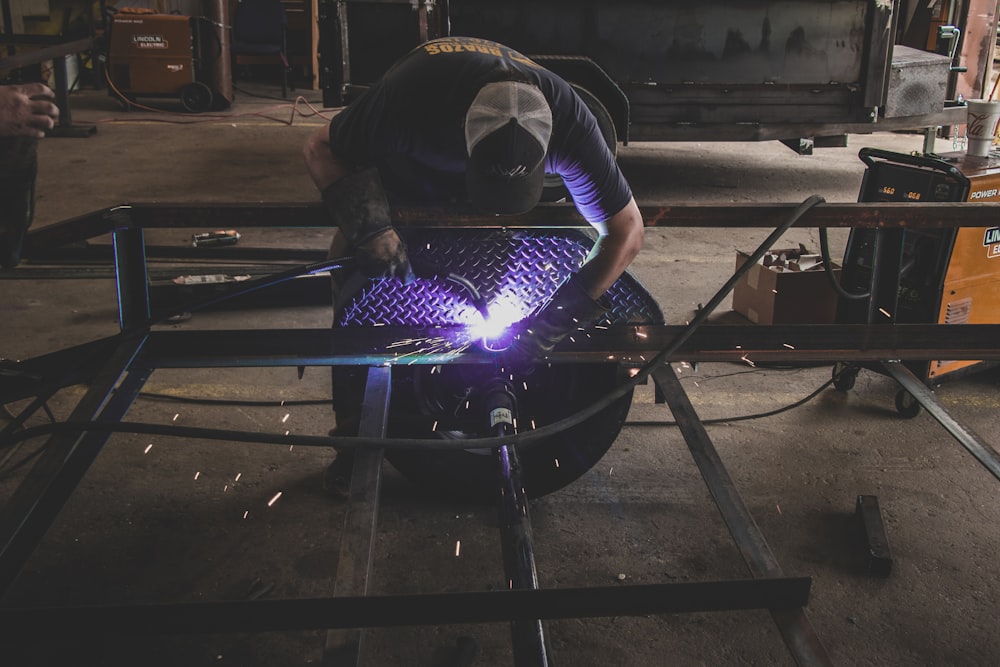 person welding black vehicle frame