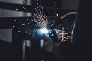 Welding sparks flying as a technician repairs a car chassis