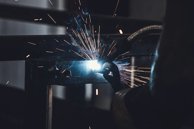 Workshop scene showing skilled workers welding iron products with sparks flying.
