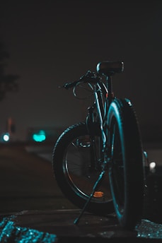 a bicycle parked on the side of a road at night