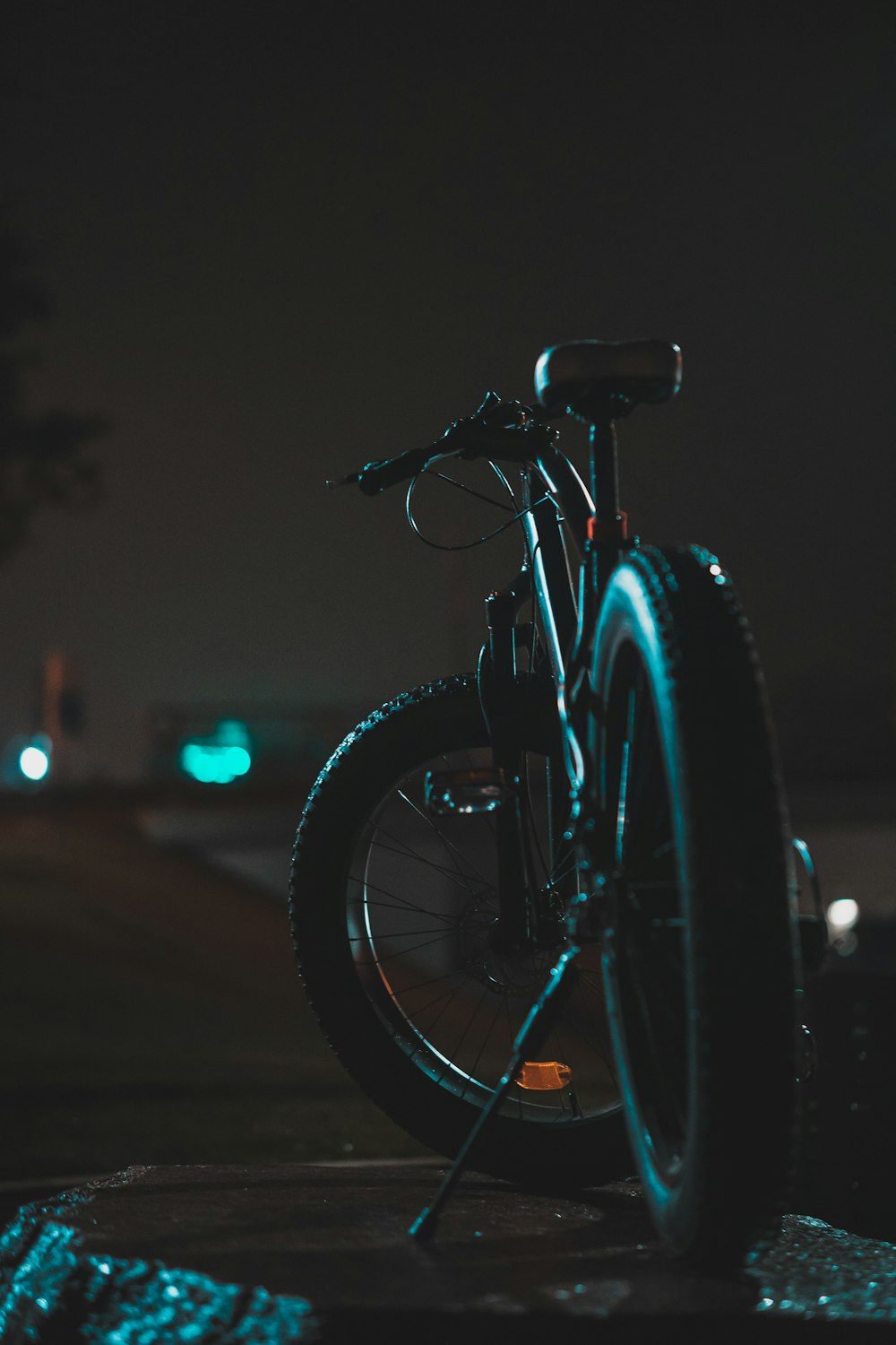 a bicycle parked on the side of a road at night