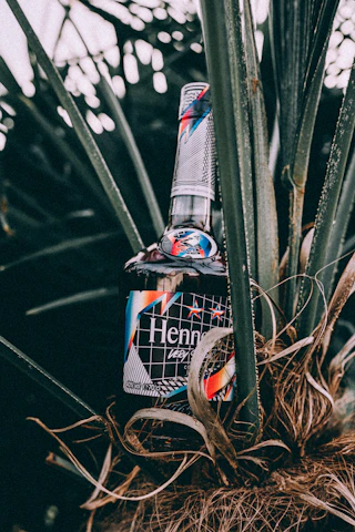 A bottle of Gosattuu surrounded by roasted chickpeas and fresh green leaves, highlighting its natural farm origins.