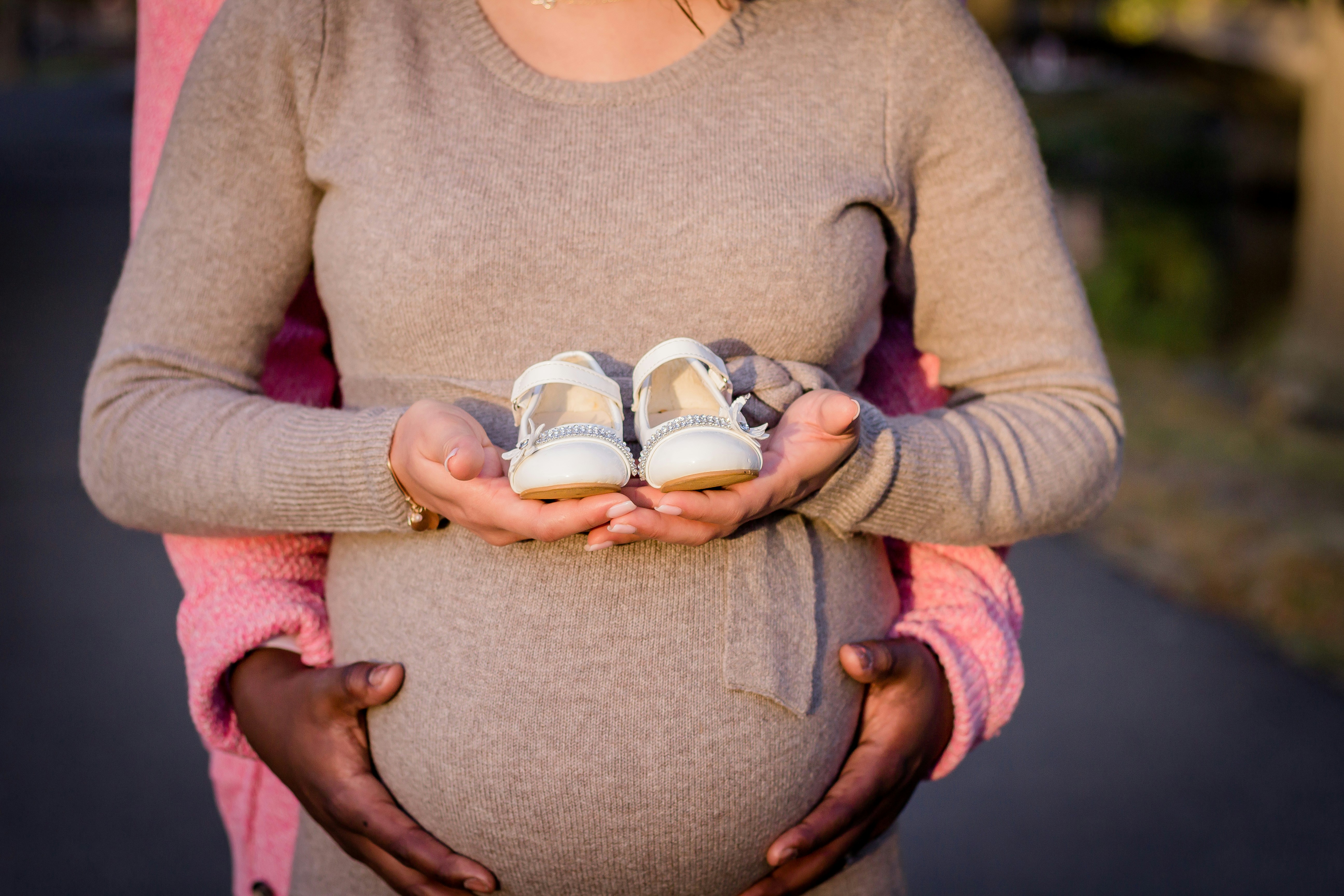 pregnant woman holding baby shoes