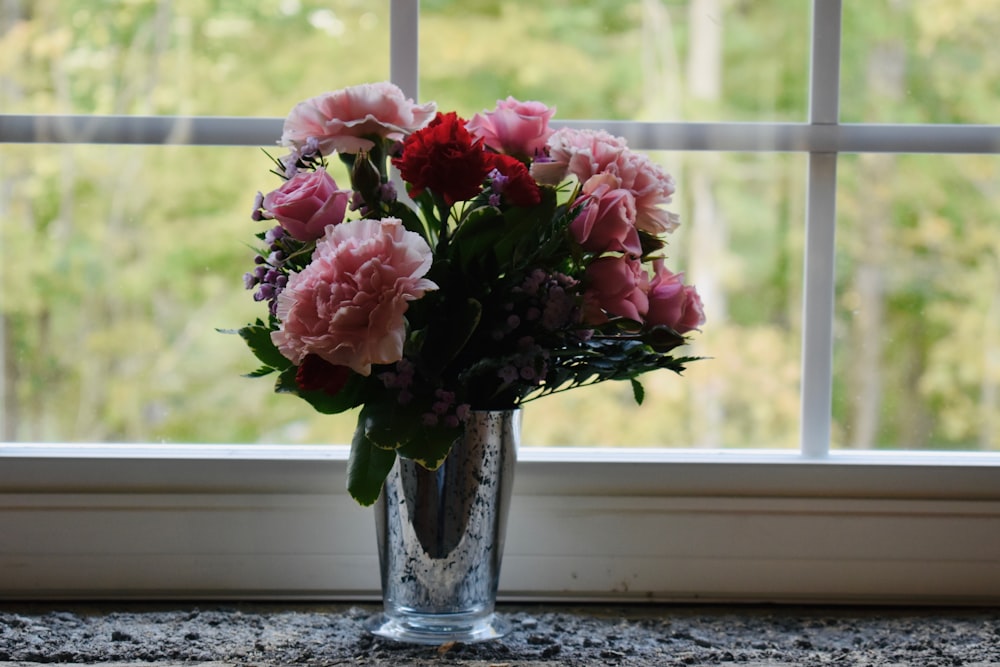 un vaso di fiori seduto sul davanzale di una finestra