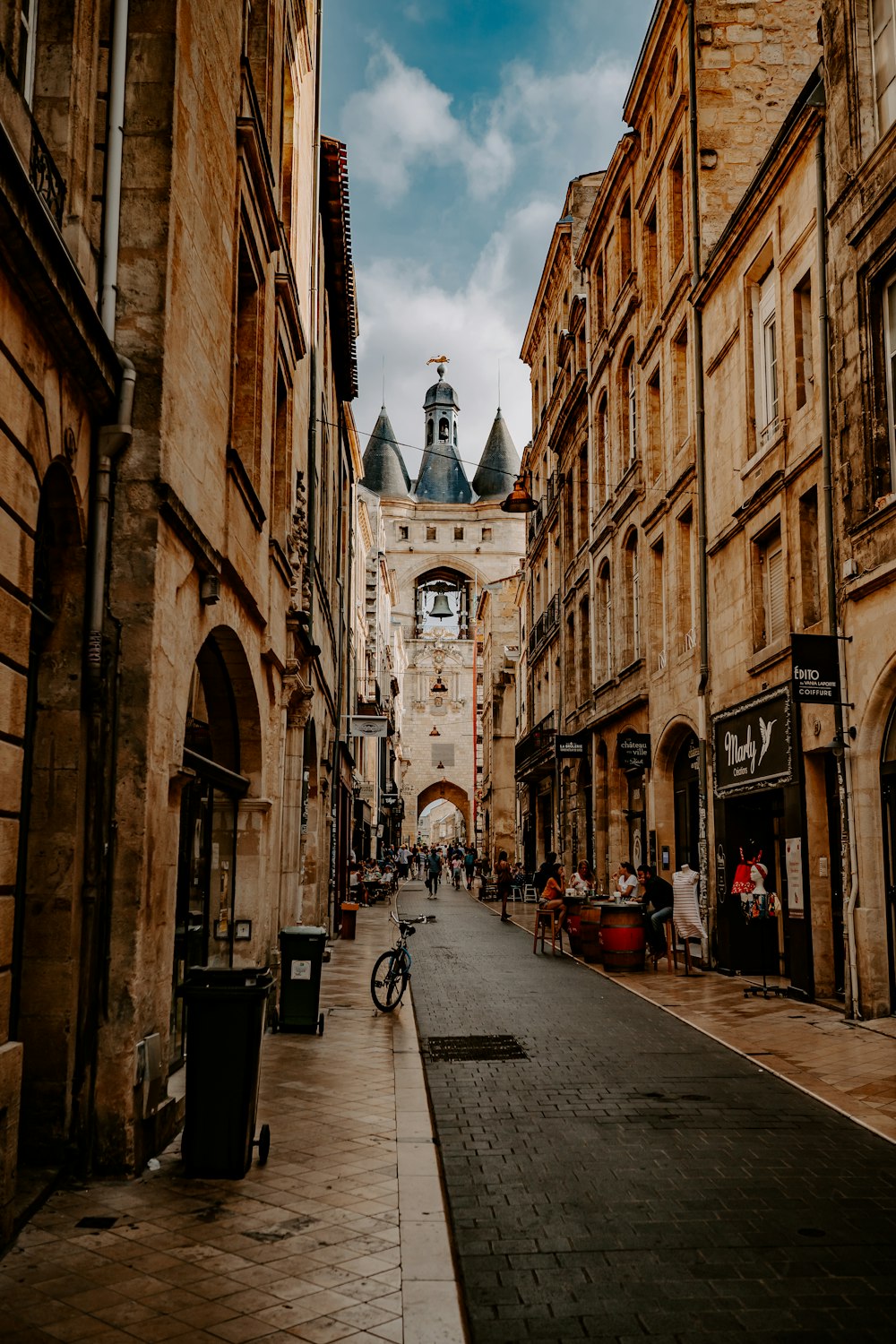 people walking on pathway near buildings under white and blue skies during daytime