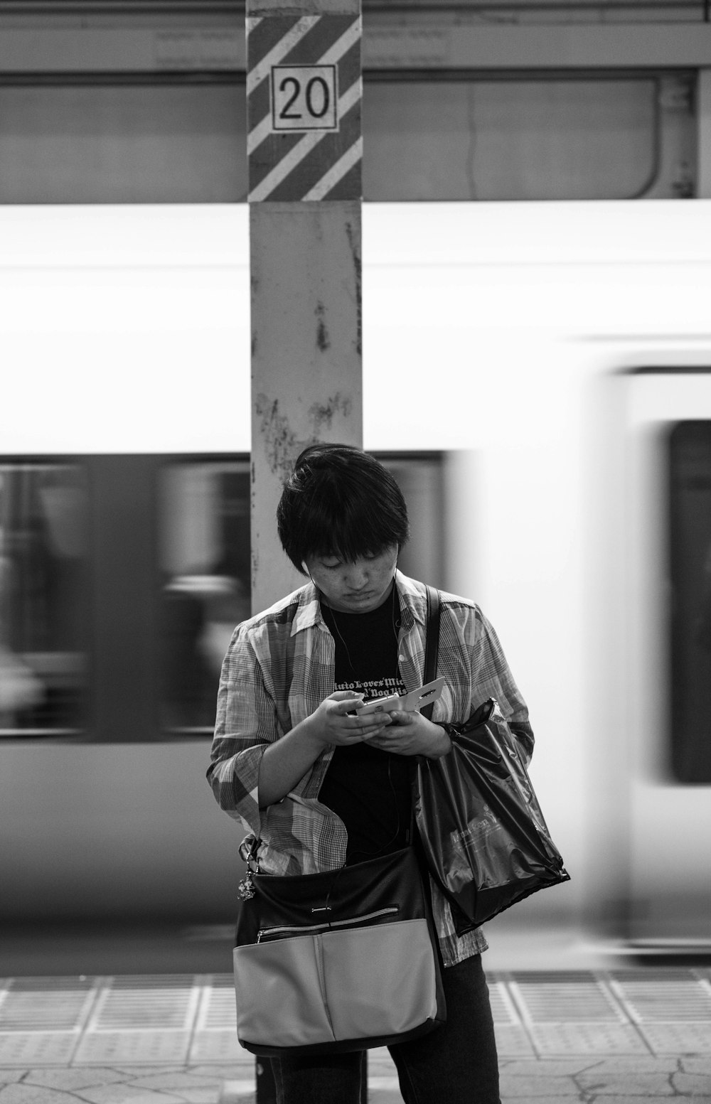 Fotografía en escala de grises de un hombre usando el teléfono mientras está de pie