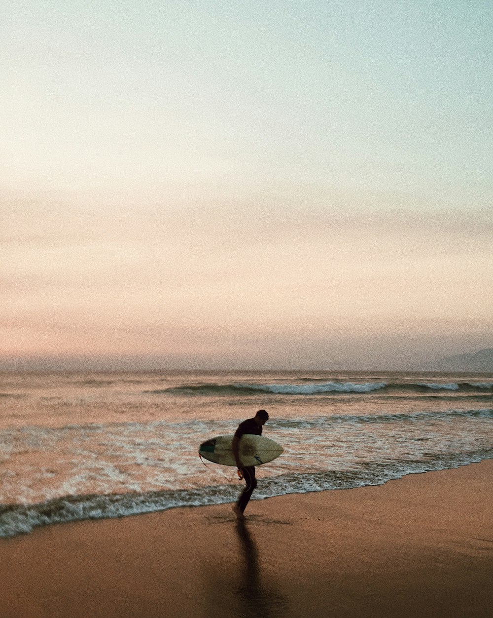 uomo che trasporta tavola da surf in riva al mare