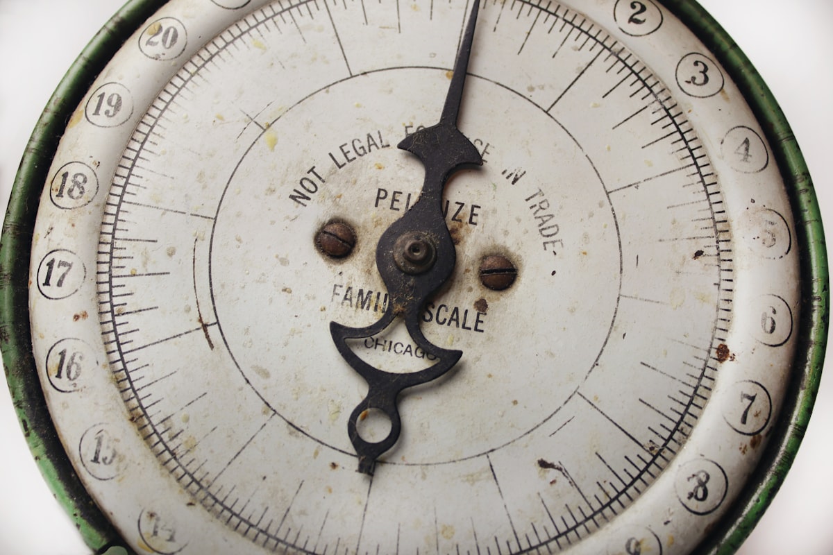 A compass resting on a dark wooden surface, its needle pointing forward with quiet certainty