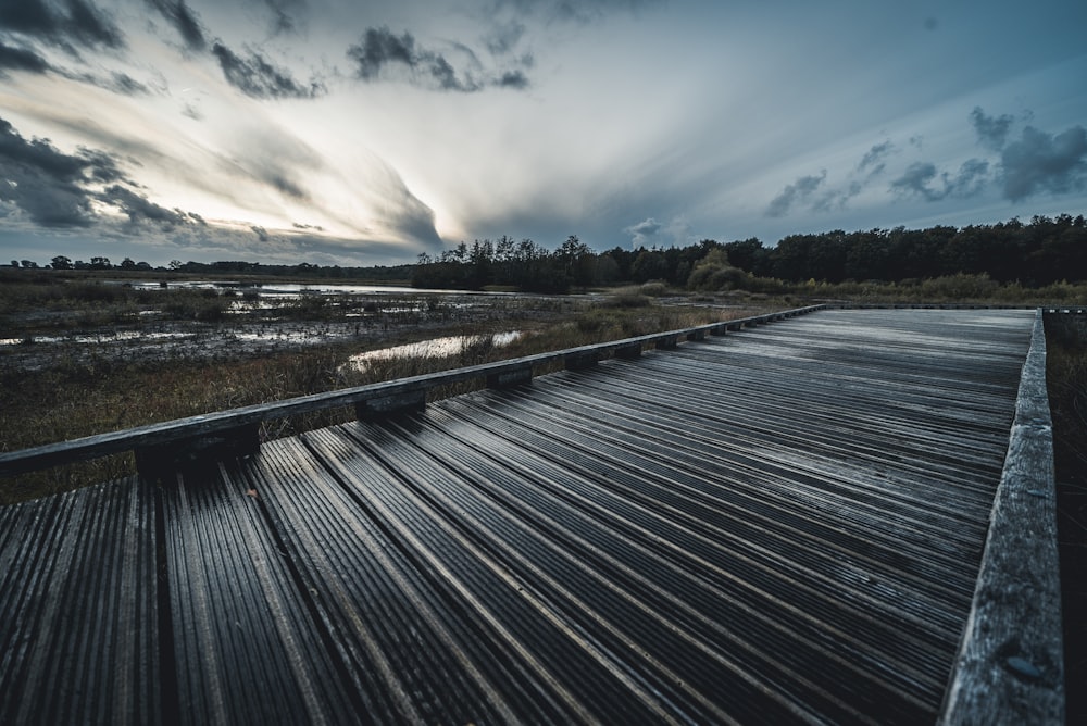 wooden pathway under a cloudy sky during daytime