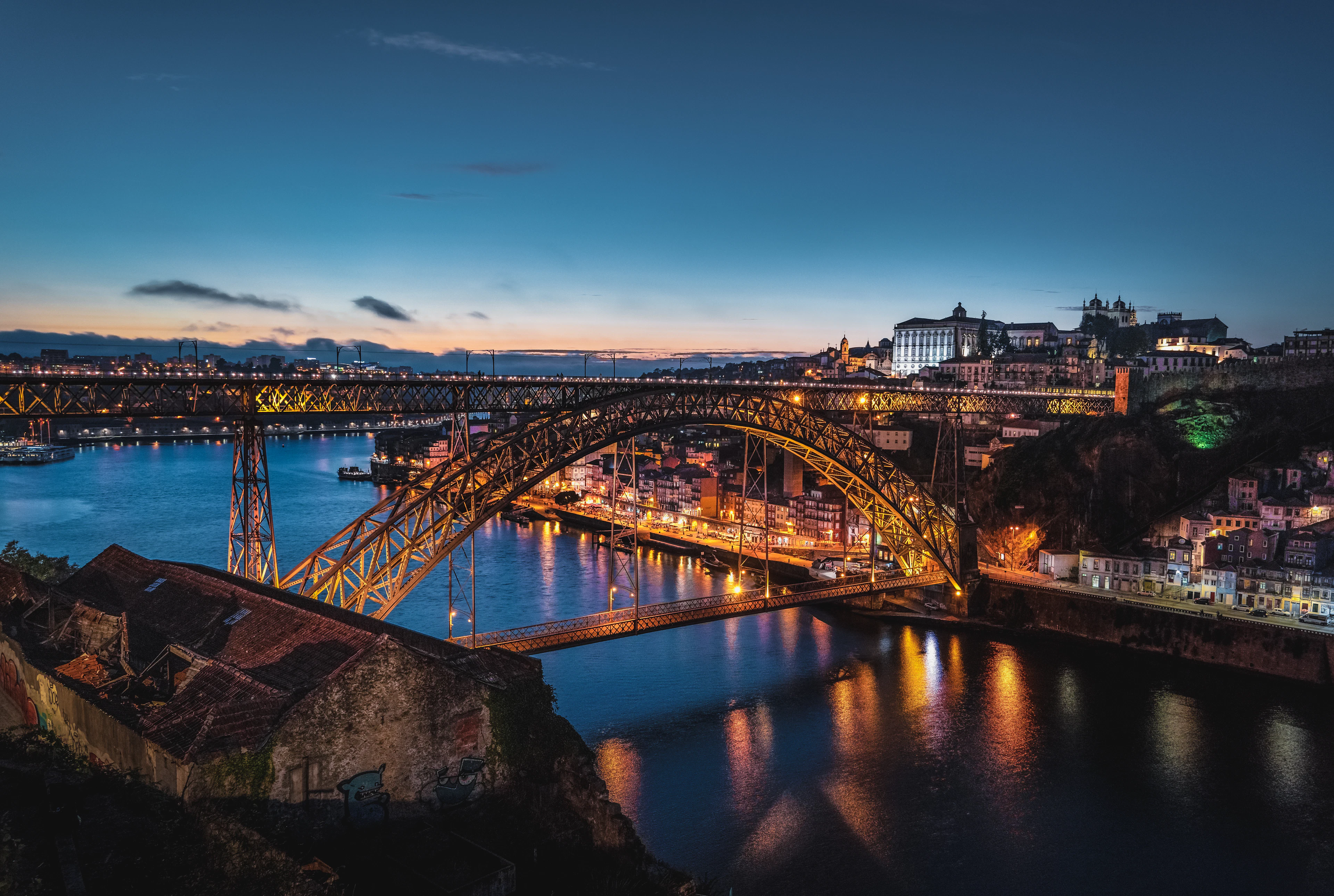 The double-deck iron arch of the Dom Luís I Bridge over the Douro river in Porto, lit at dusk