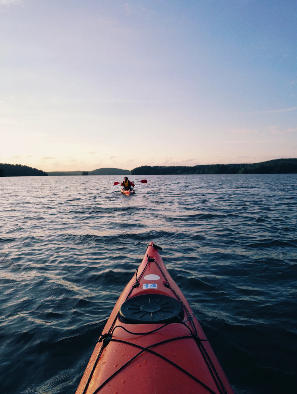 A red canoe floating on calm water, ready for the morning paddle session
