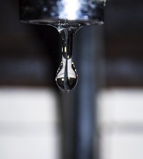 Close-up of crystal-clear water droplets falling from an Ashpure purifier tap.