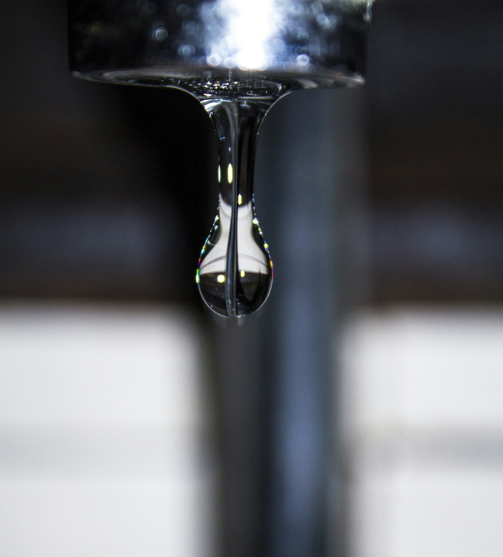 Close-up of a pure water droplet reflecting a high-tech water treatment facility in a clean, sterile environment.