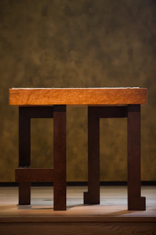 Finished wooden table with warm oak tones set against a soft cream background.
