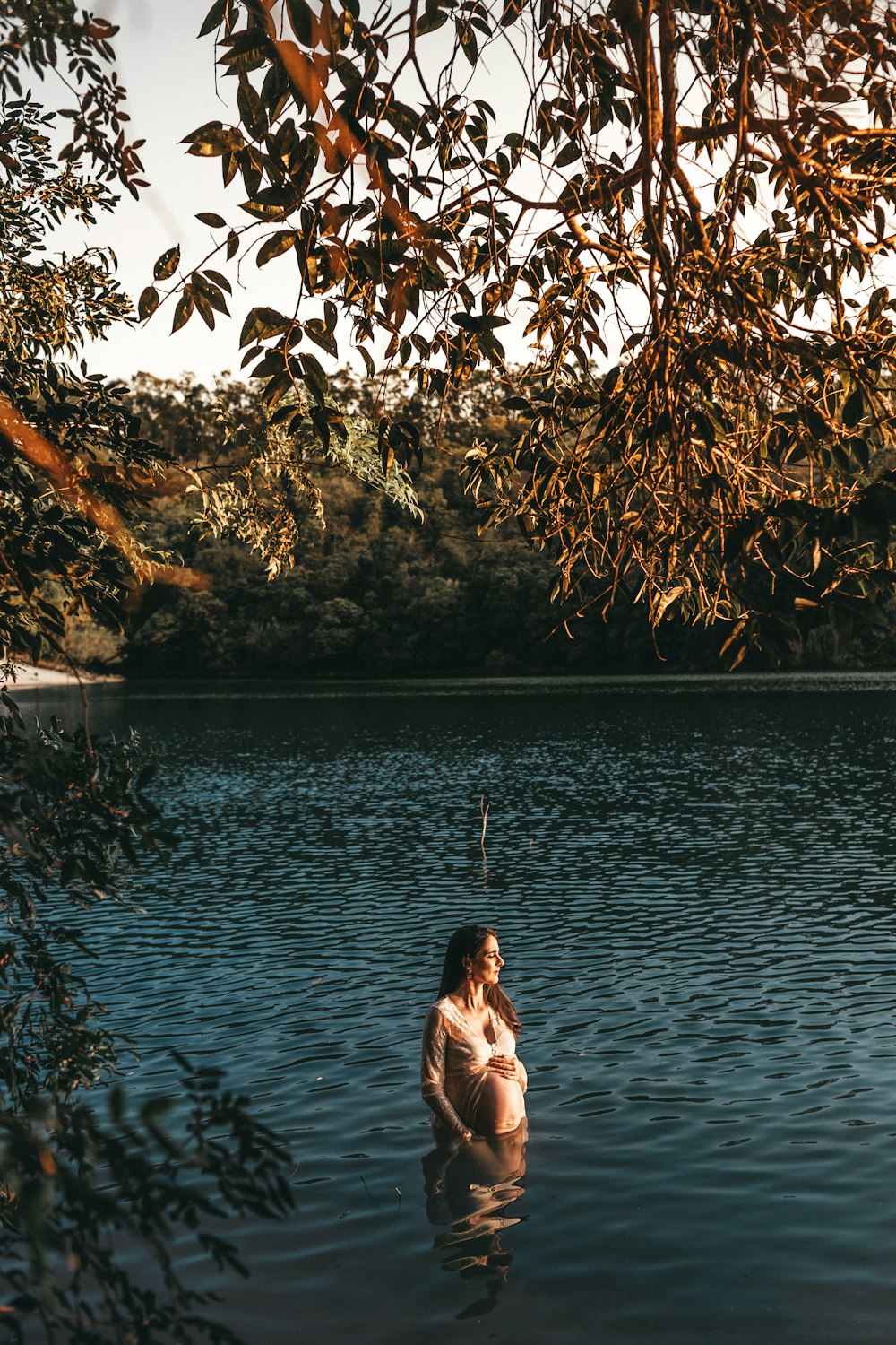 donna incinta in piedi in uno specchio d'acqua durante il giorno