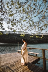 pregnant woman standing on wooden dock under tree