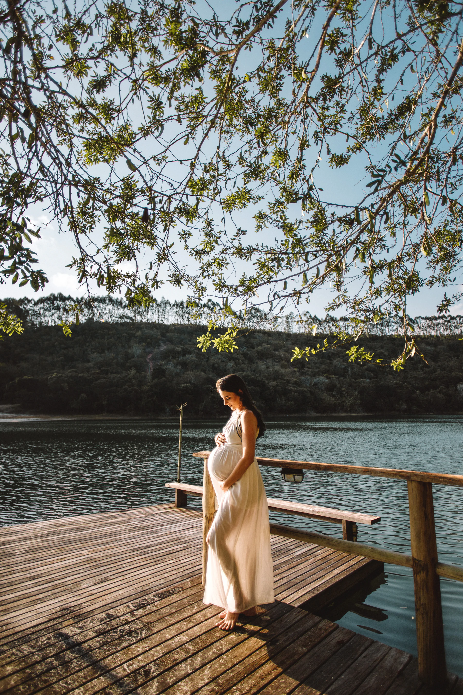 An expectant mother standing quietly beneath a tree