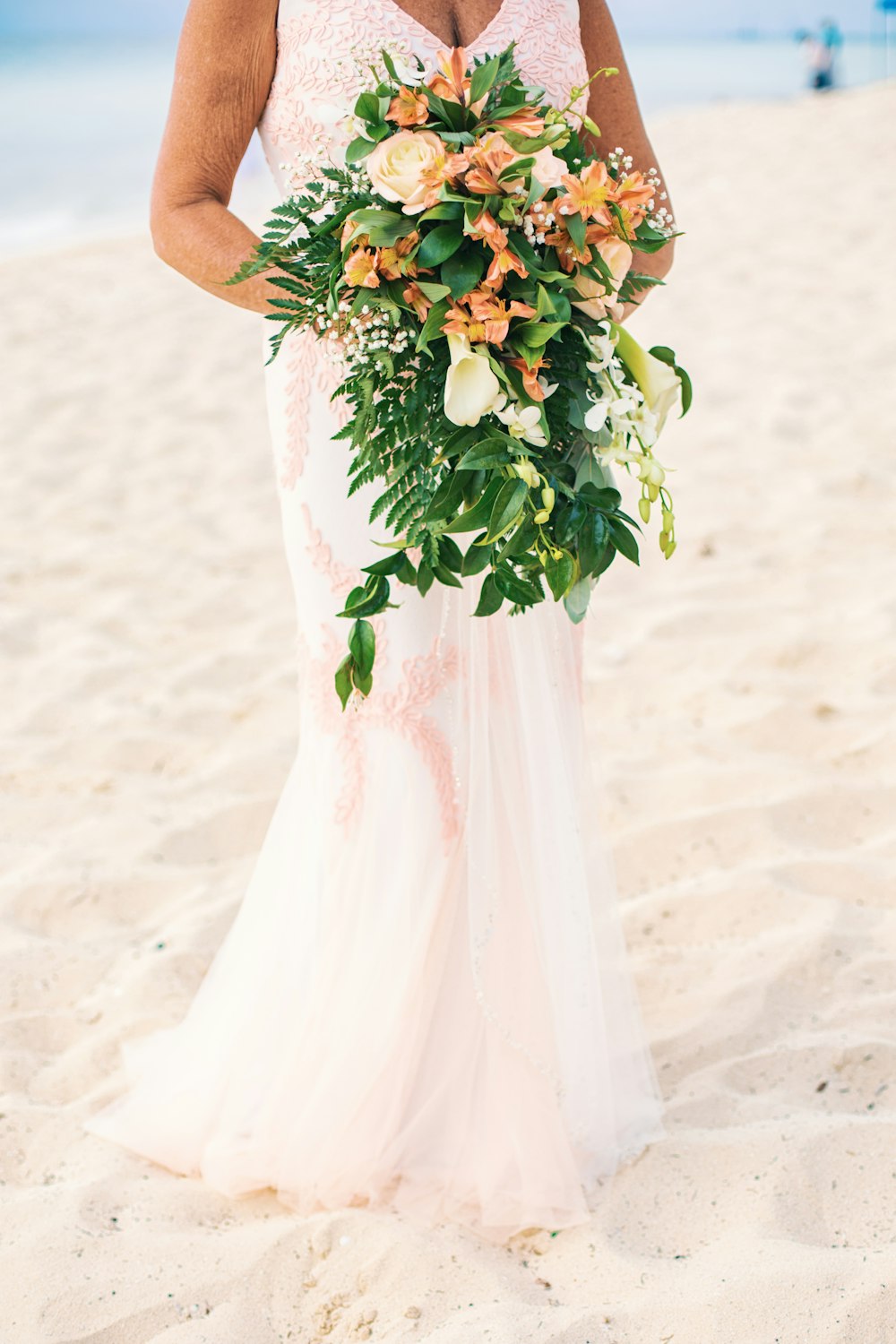 a woman holding a bouquet of flowers on a beach