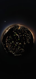A spherical 360-degree view of a city at night, with illuminated streets and buildings forming a circular pattern. In the background, a bright celestial body is visible in the dark sky, adding a cosmic element to the scene.