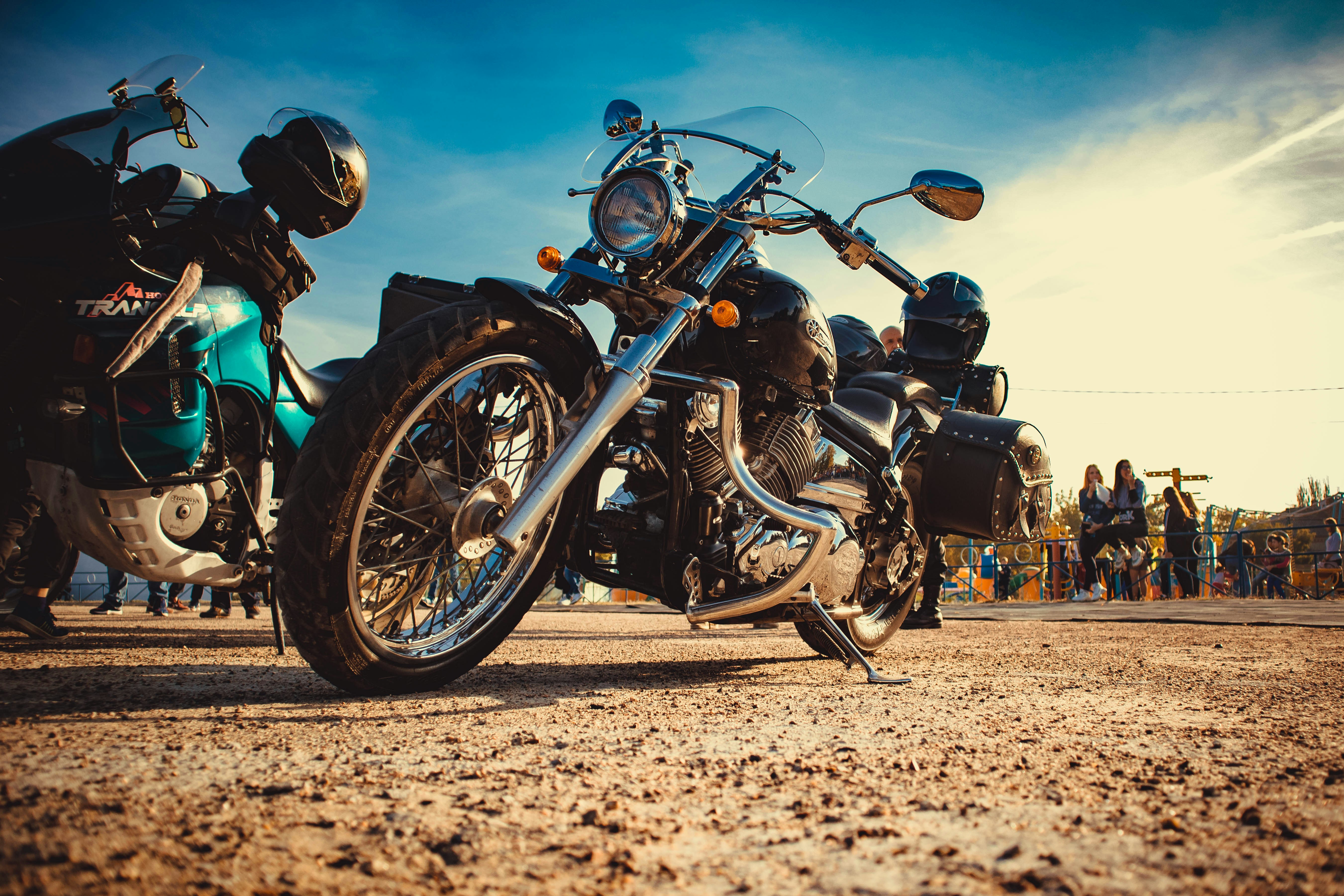 people standing near road and cruiser motorcycles parking beside road under blue and white skies during daytime