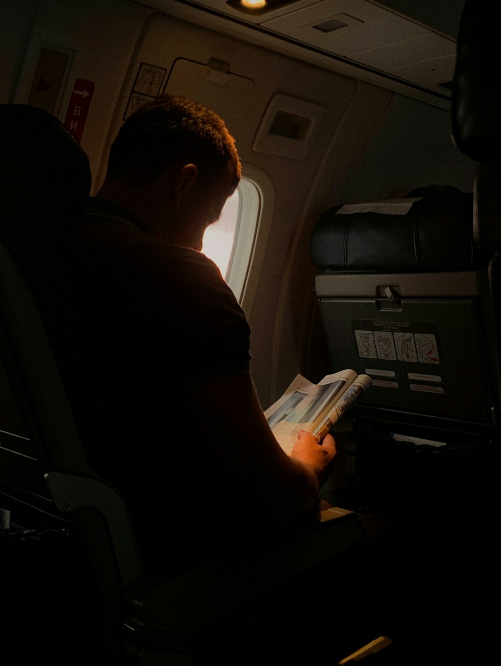 man reading book in airplane