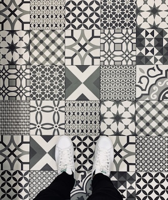 Model wearing white Nike sneakers stepping on a minimalist black and yellow tiled floor.