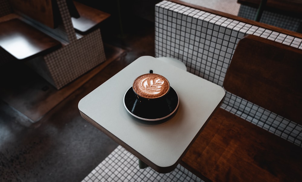 Cappuccino in schwarzem Becher auf dem Tisch