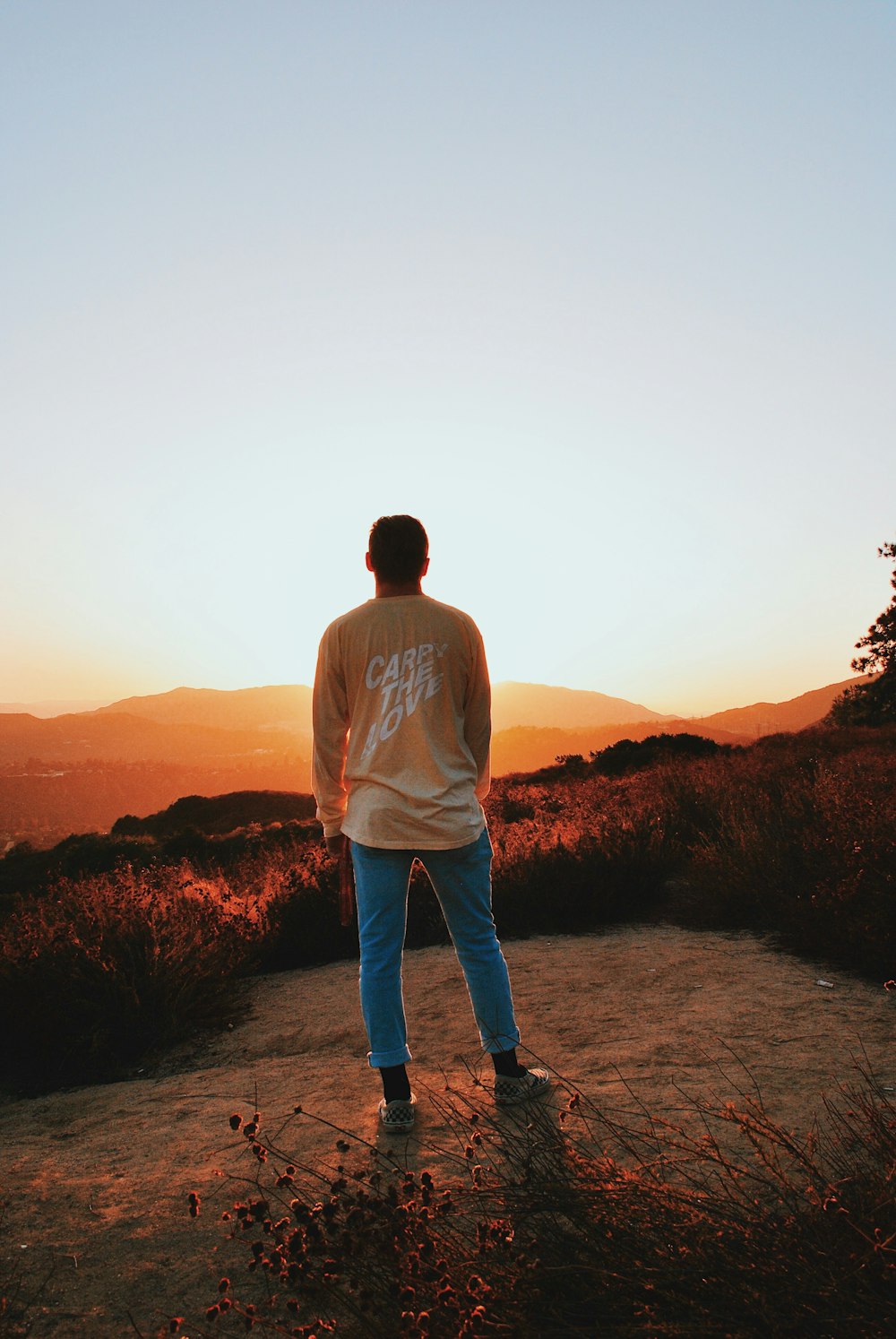 unknown person in orange top and blue pants standing outdoors