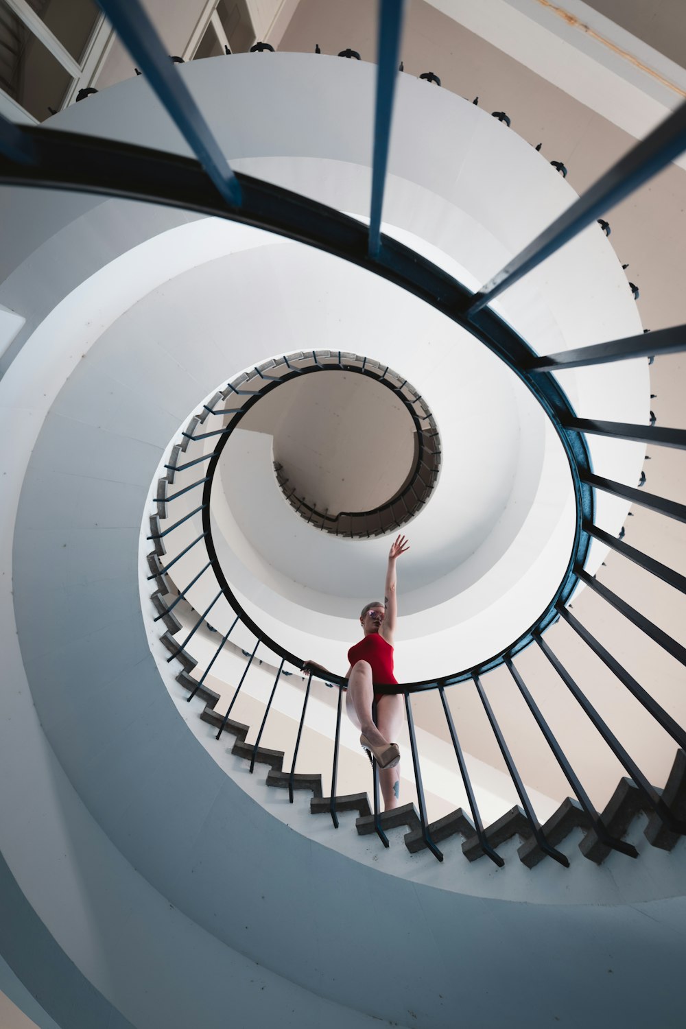 a woman in a red shirt is standing on a spiral staircase