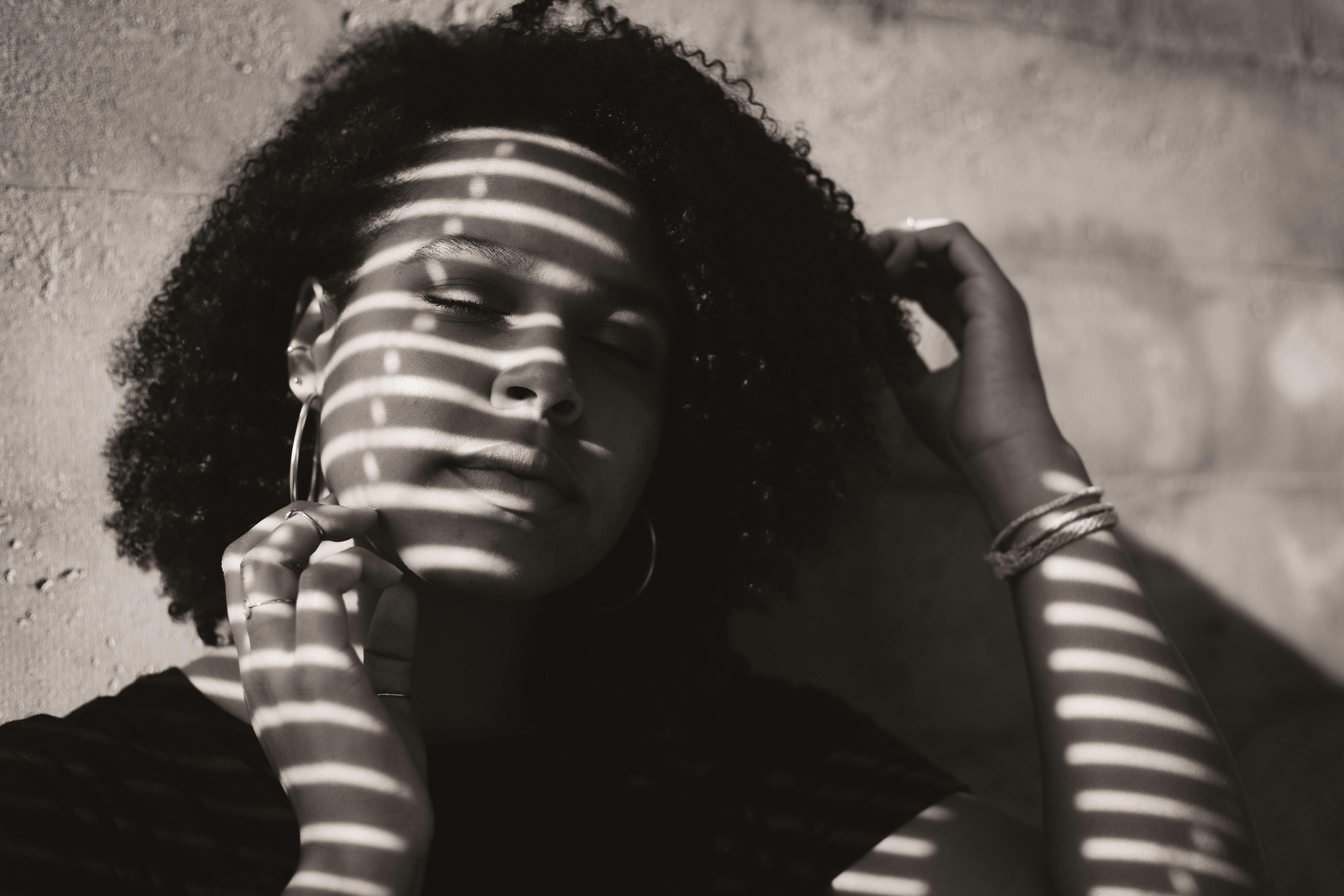 Fotografía en escala de grises de mujer apoyada en la pared