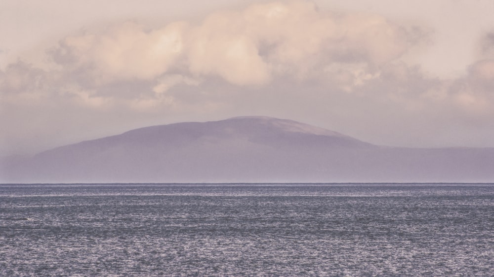 body of water near mountain at golden hour