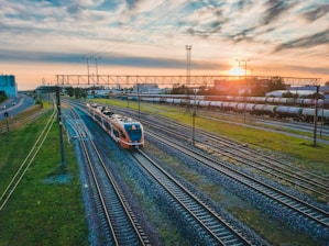 a train traveling down train tracks next to a lush green field
