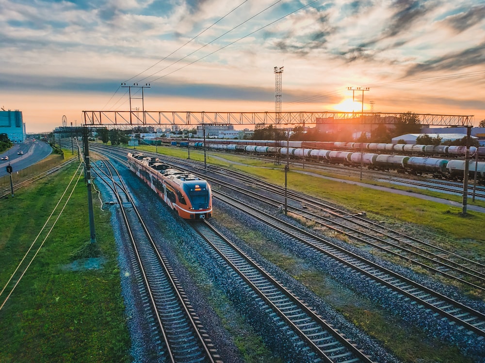 un train descendant les voies ferrées à côté d’un champ verdoyant