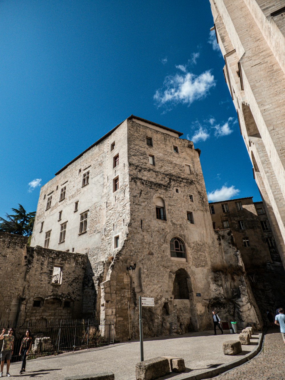 people walking near road beside buildings under blue and white skies during daytime