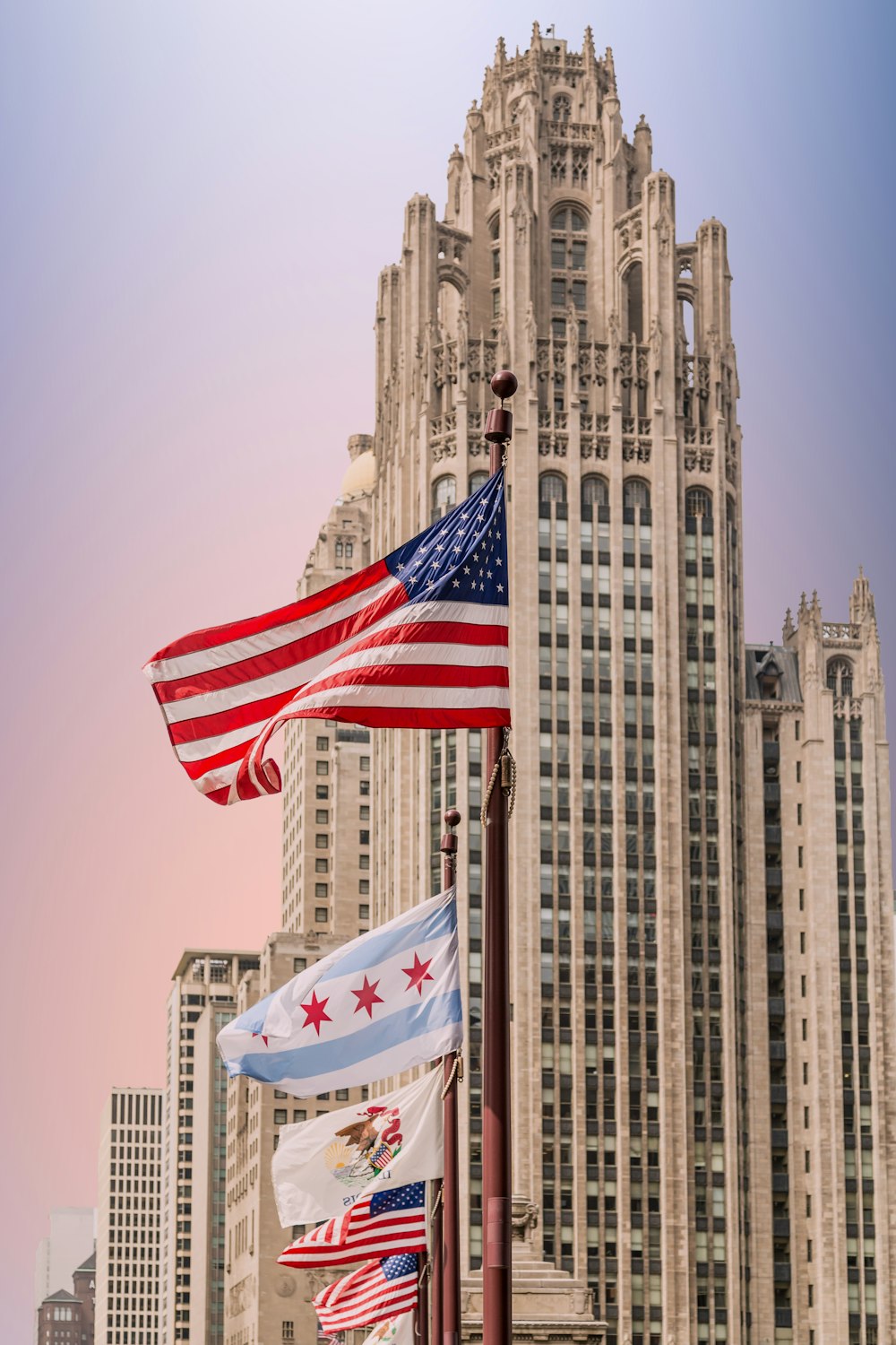 a group of flags flying in front of a tall building