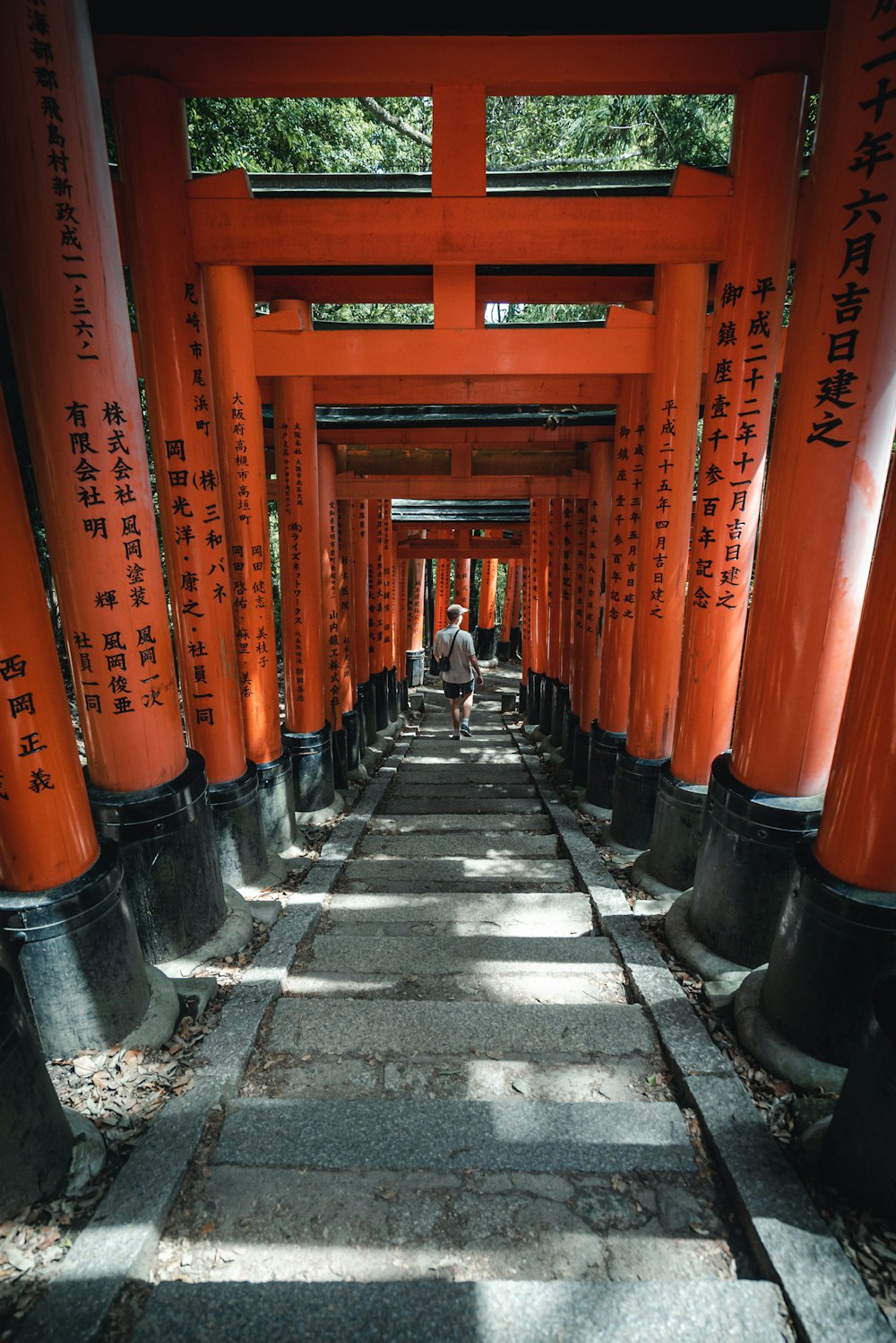 a man walking down a walkway lined with orange tori tori tori tori tori tori tori