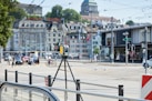 a street scene with focus on a camera on a tripod