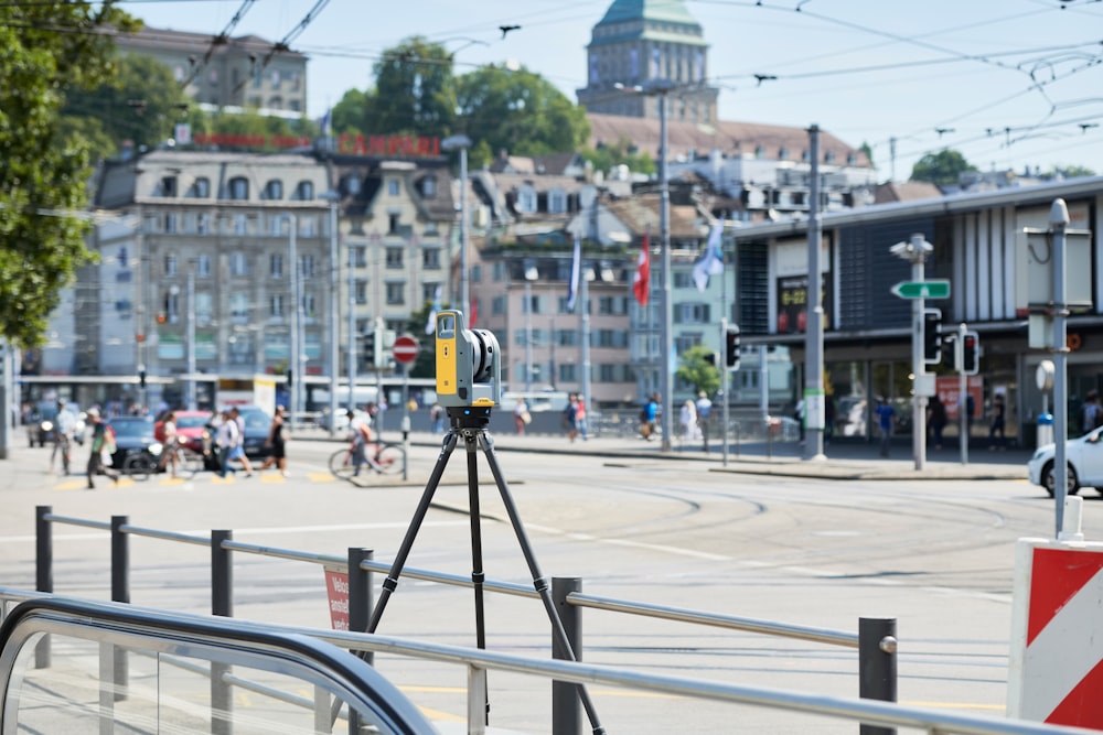 a street scene with focus on a camera on a tripod